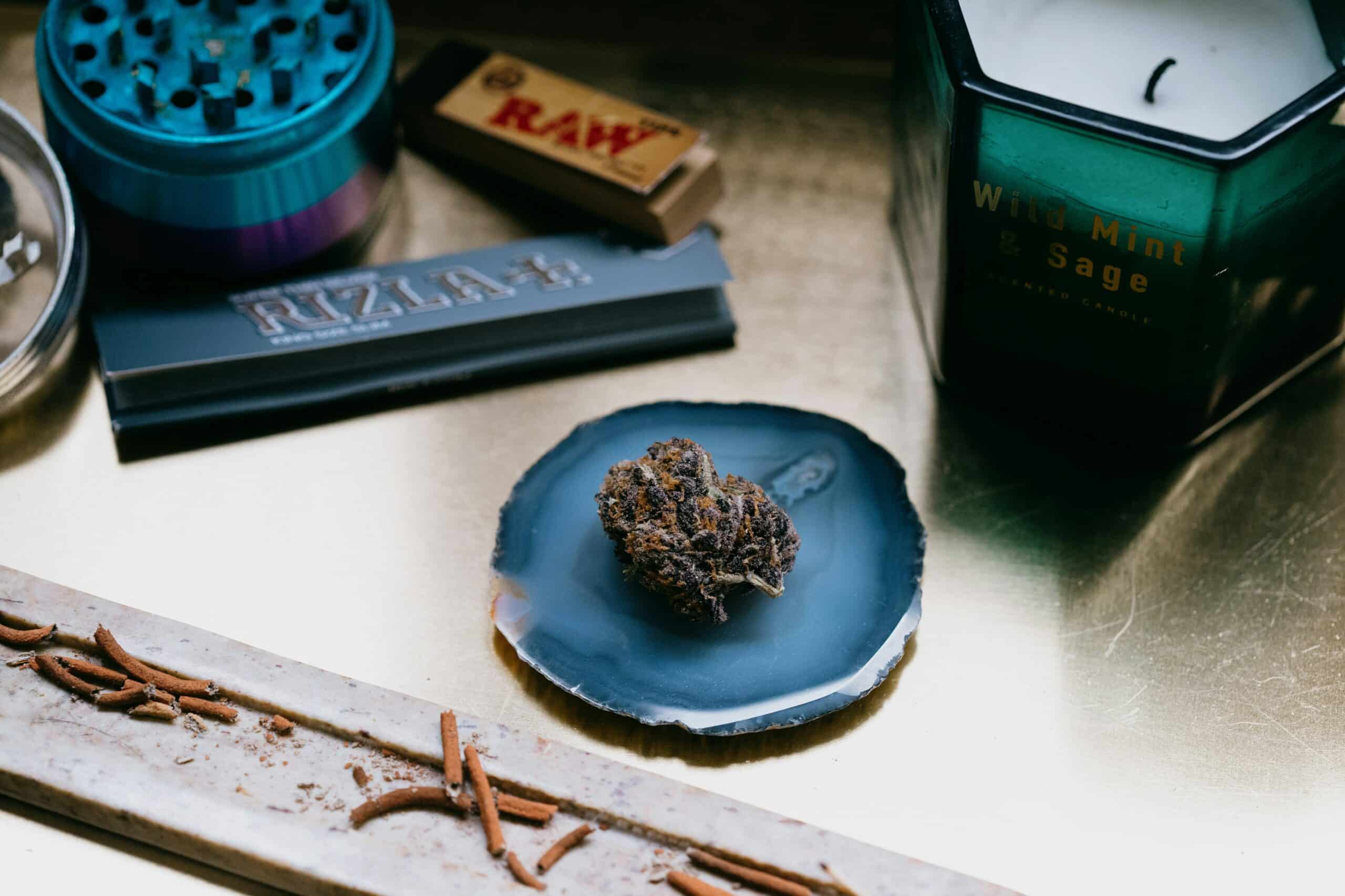 cannabis flower on stone with incense and gear