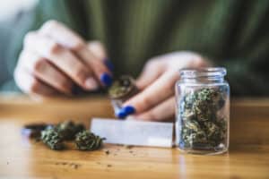 Woman rolling a marijuana joint at home.